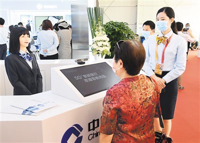 随着人们支付习惯的变化,银行积极谋求服务转型。图为2020年中国国际服务贸易交易会上,参观者(右前)与中国建设银行带来的仿真机器人大堂经理(左一)交流。 新华社记者 任 超摄