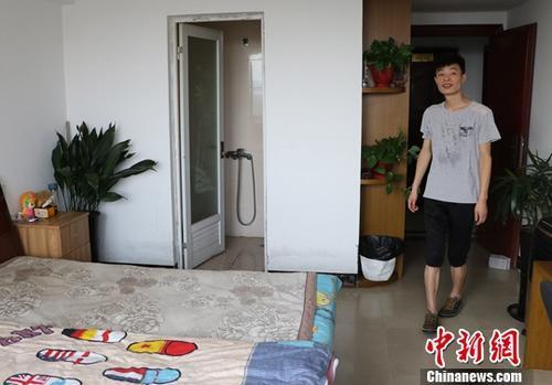 资料图:一名小伙展示自己通过当地租房平台找到的房子。 中新社记者 王刚 摄