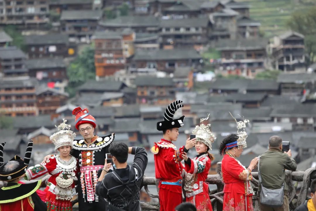 ▲10月7日,游客穿着民族服装在贵州省雷山县西江千户苗寨观景台拍照留念。新华社发(林世康 摄)