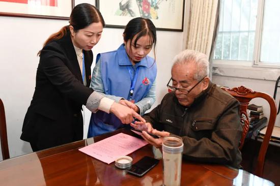 吴兴区飞英街道米行街社区普查人员指导一名孤寡老人在家中使用电子采集设备完成人口普查签名