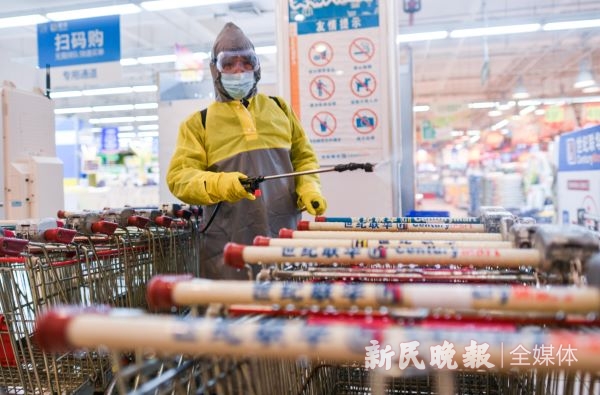 图说:昨晚十点,仙霞路上一家超市结束营业,工作人员对购物车进行消毒 新民晚报记者 陈梦泽 摄